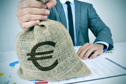 スペインから来た実業家が机でお金の入った袋を持っています。