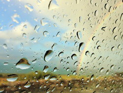 虹を背景に窓に落ちる雨が、スペインの鮮やかな色合いと対照的です。