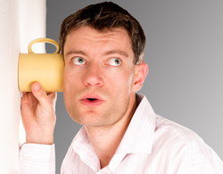 スペインでコーヒーカップを耳に当てている男性。