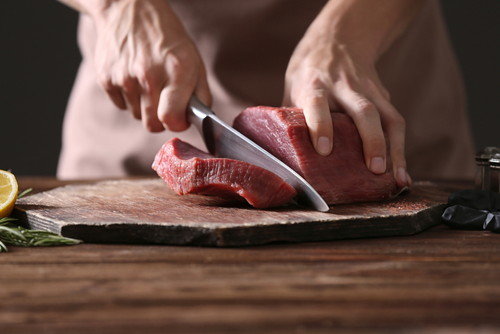 スペインでまな板の上で肉をスライスしている人。