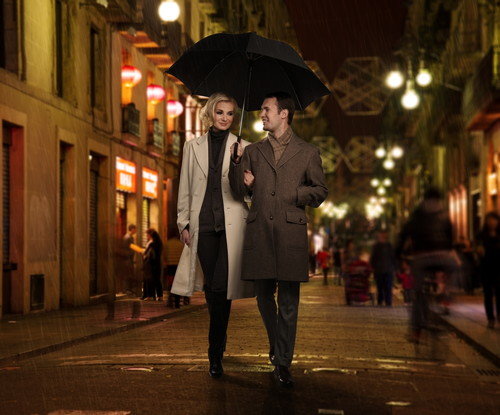 スペインの街路を傘をさして歩く男女。