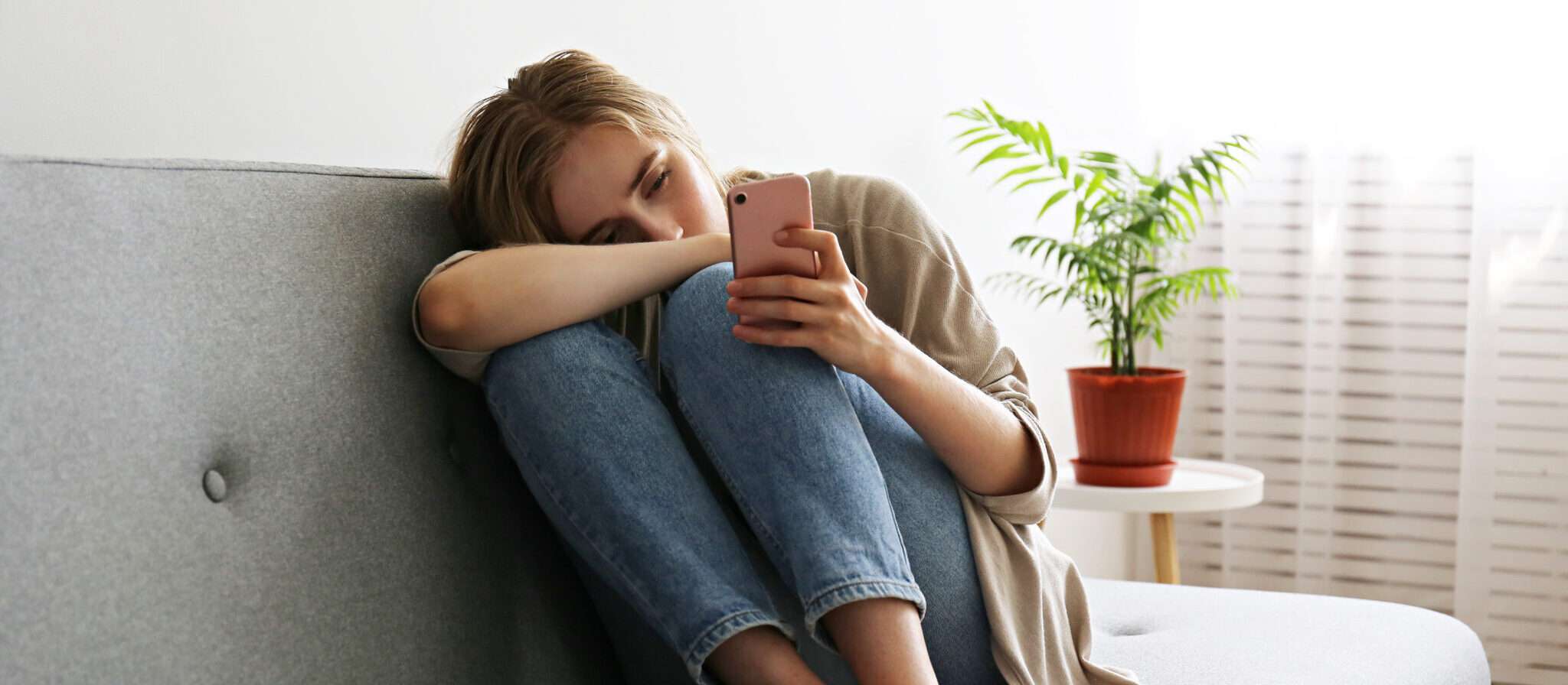 スペインで女性が携帯電話を手にソファに座っている。
