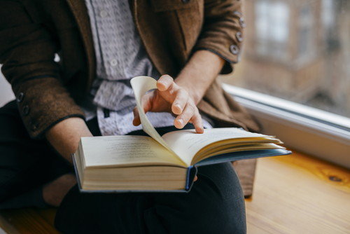 スペインの美しさに浸りながら、窓の前で本を読む男性。