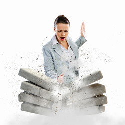 スペインから来た女性実業家がレンガの壁に向かってレンガを投げている。