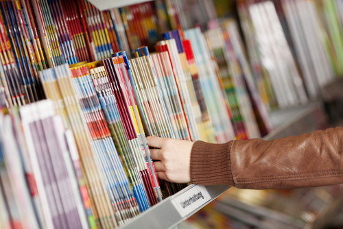 書店の棚からスペインの雑誌を手に取る人。