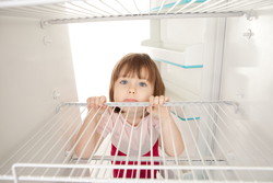 スペインの開いた冷蔵庫から顔を覗かせる少女。