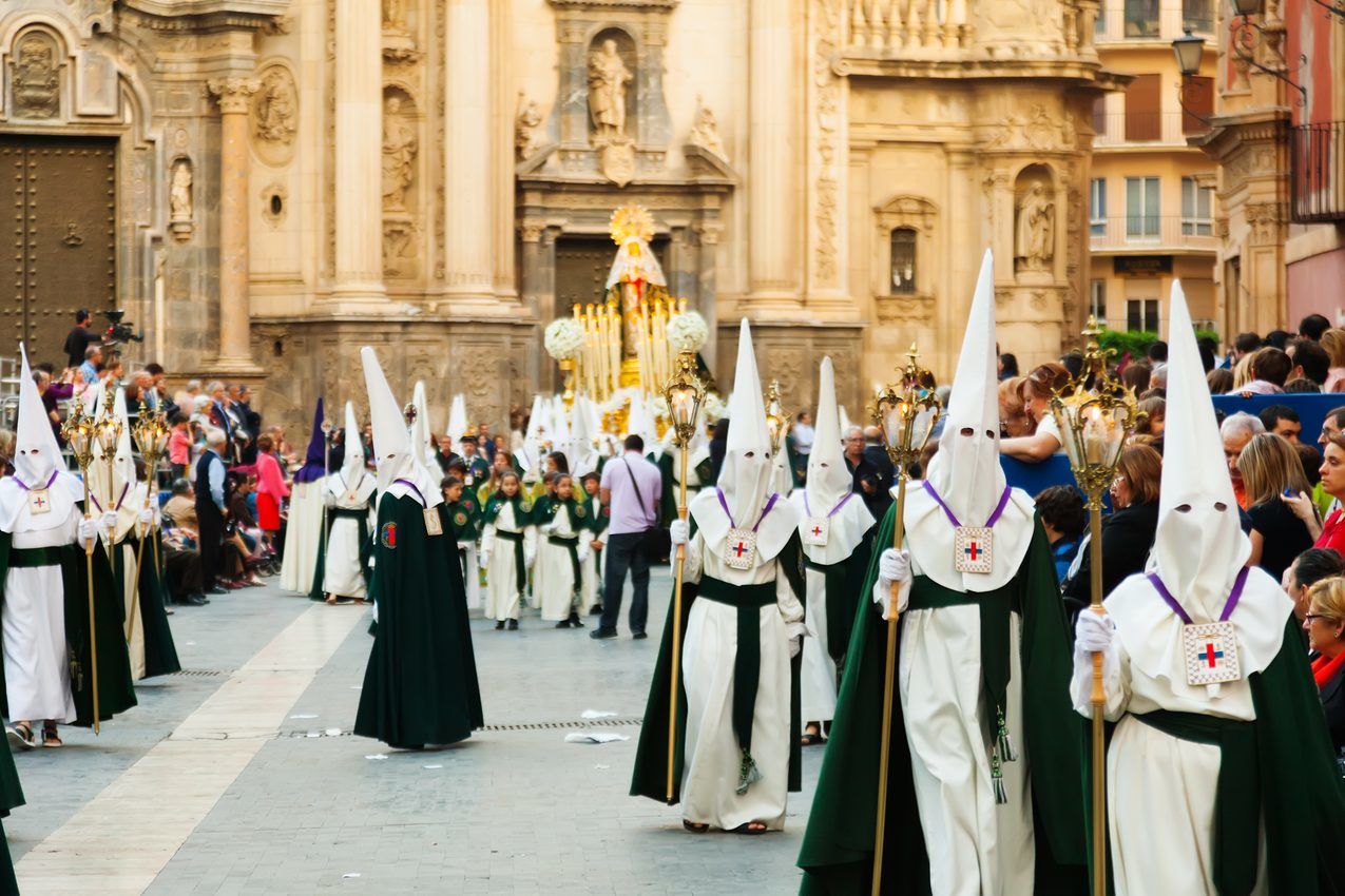 スペインの通りを歩く白いローブを着た人々のグループ。