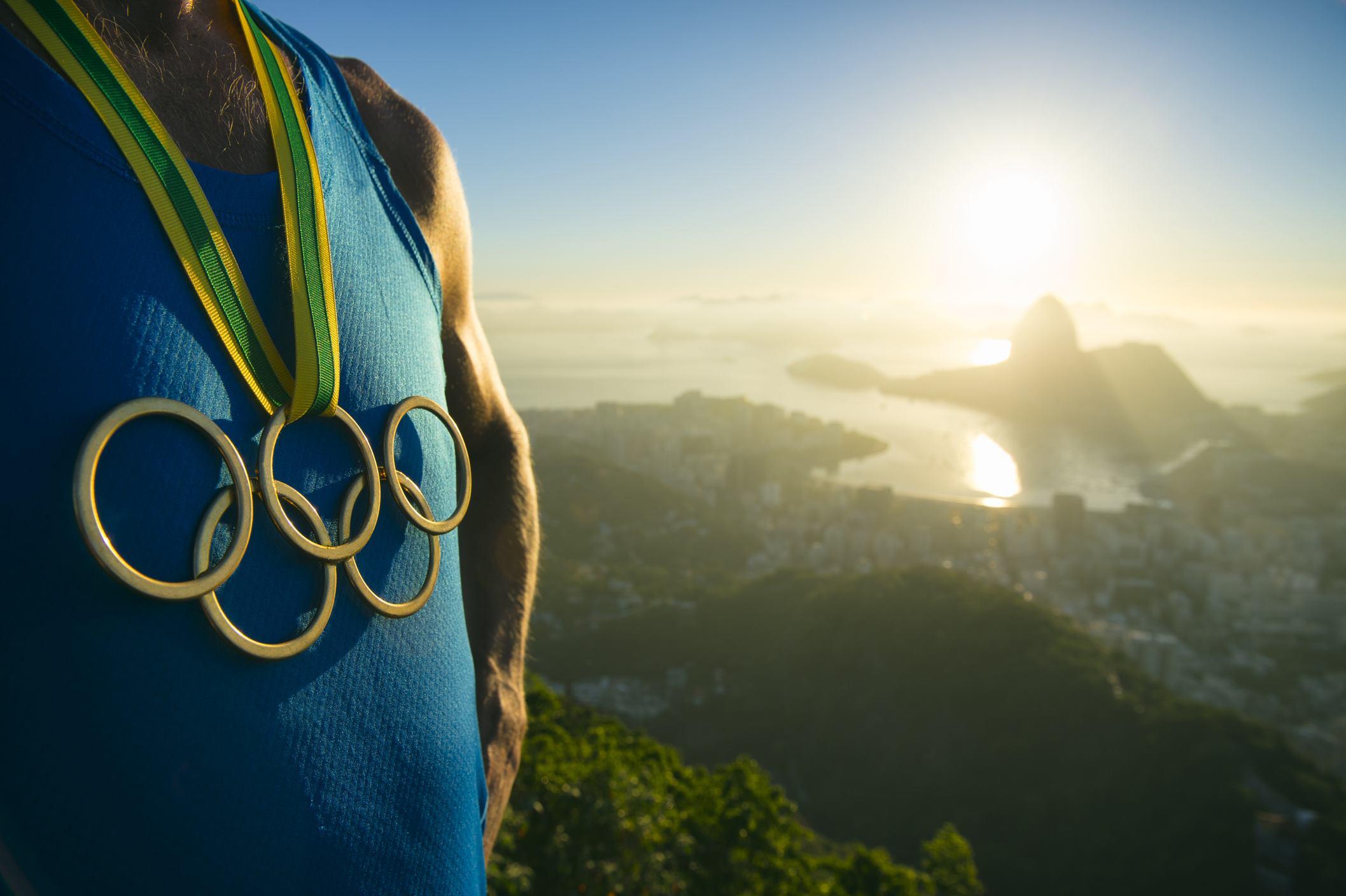 スペインの山の頂上に立つ、オリンピックのメダルを持った男性。