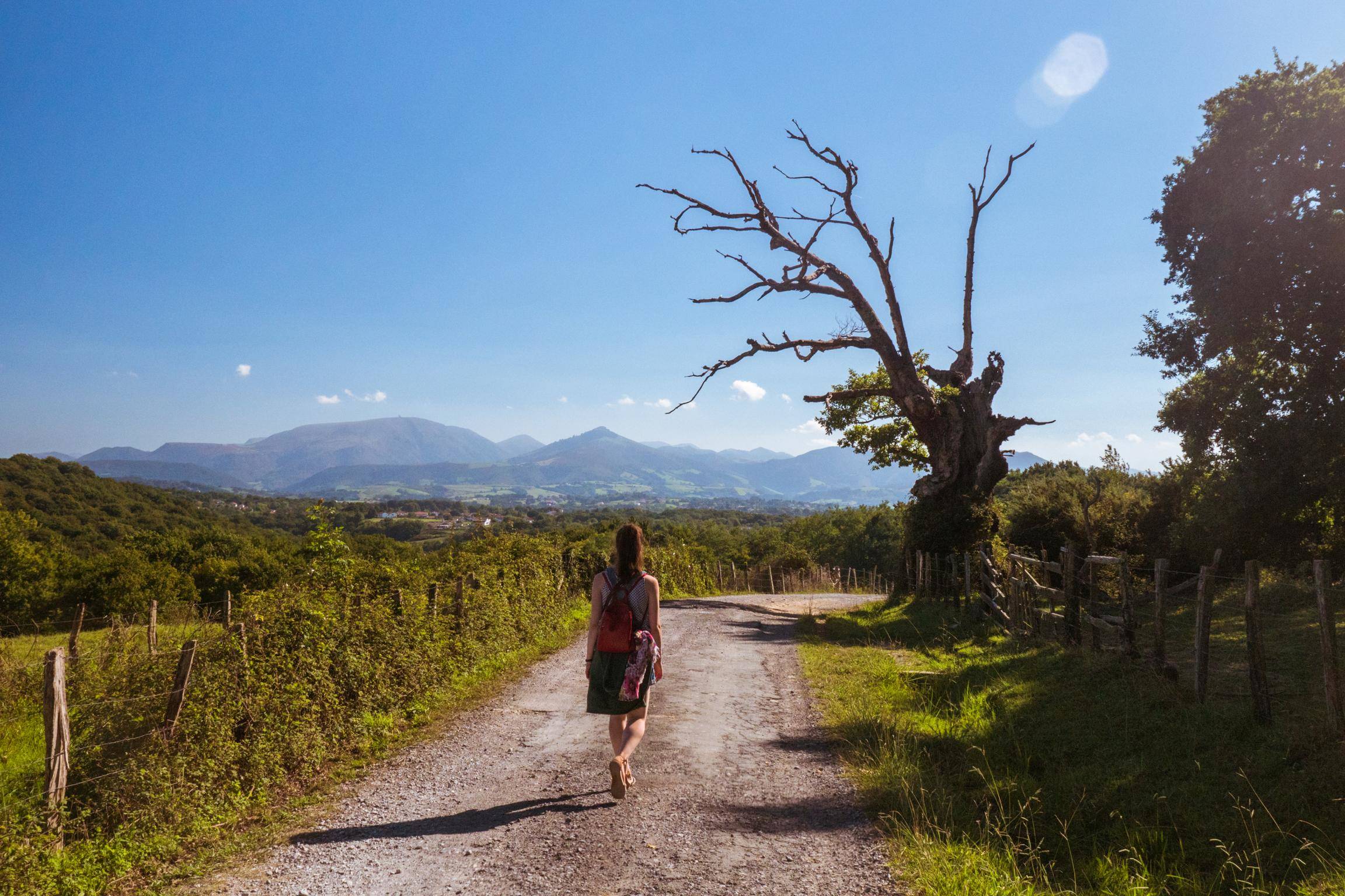 山を背景にスペインの未舗装の道路を歩く女性。