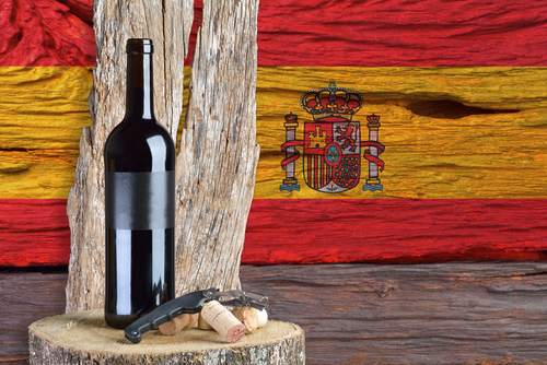 説明: スペインの旗がある切り株の上にワインのボトルがあります。