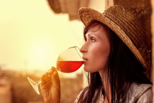 スペインをイメージした麦わら帽子をかぶって赤ワインを飲む女性。