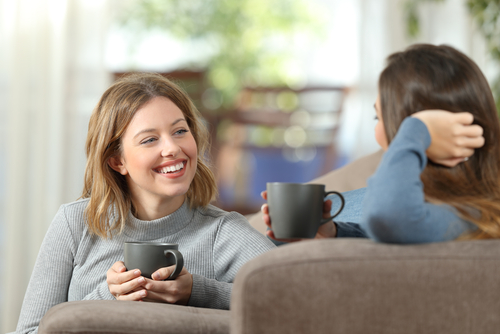 スペインでコーヒーマグを手にソファに座り、一緒に時間を楽しむ2人の女性。