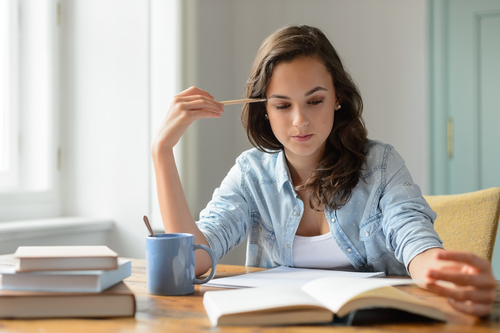女性がテーブルに座り、本を開いてコーヒーを飲みながらスペインについて読んでいます。