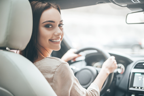 スペインで女性が笑顔で車を運転している。