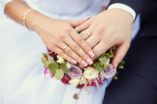 花束を持ったスペインの新郎新婦の手。