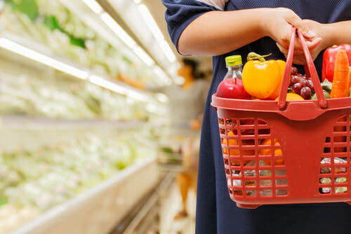 スペインから来た女性が果物や野菜でいっぱいの買い物かごを持っています。