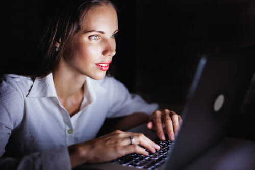 スペインで夜にラップトップ コンピューターを使用する女性。