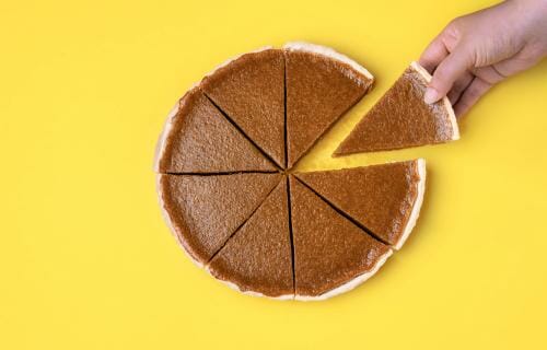 スペインでは、黄色の背景にパンプキンパイのスライスを持っている手。