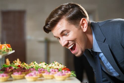 スーツを着た男性がスペイン料理のビュッフェを見ています。
