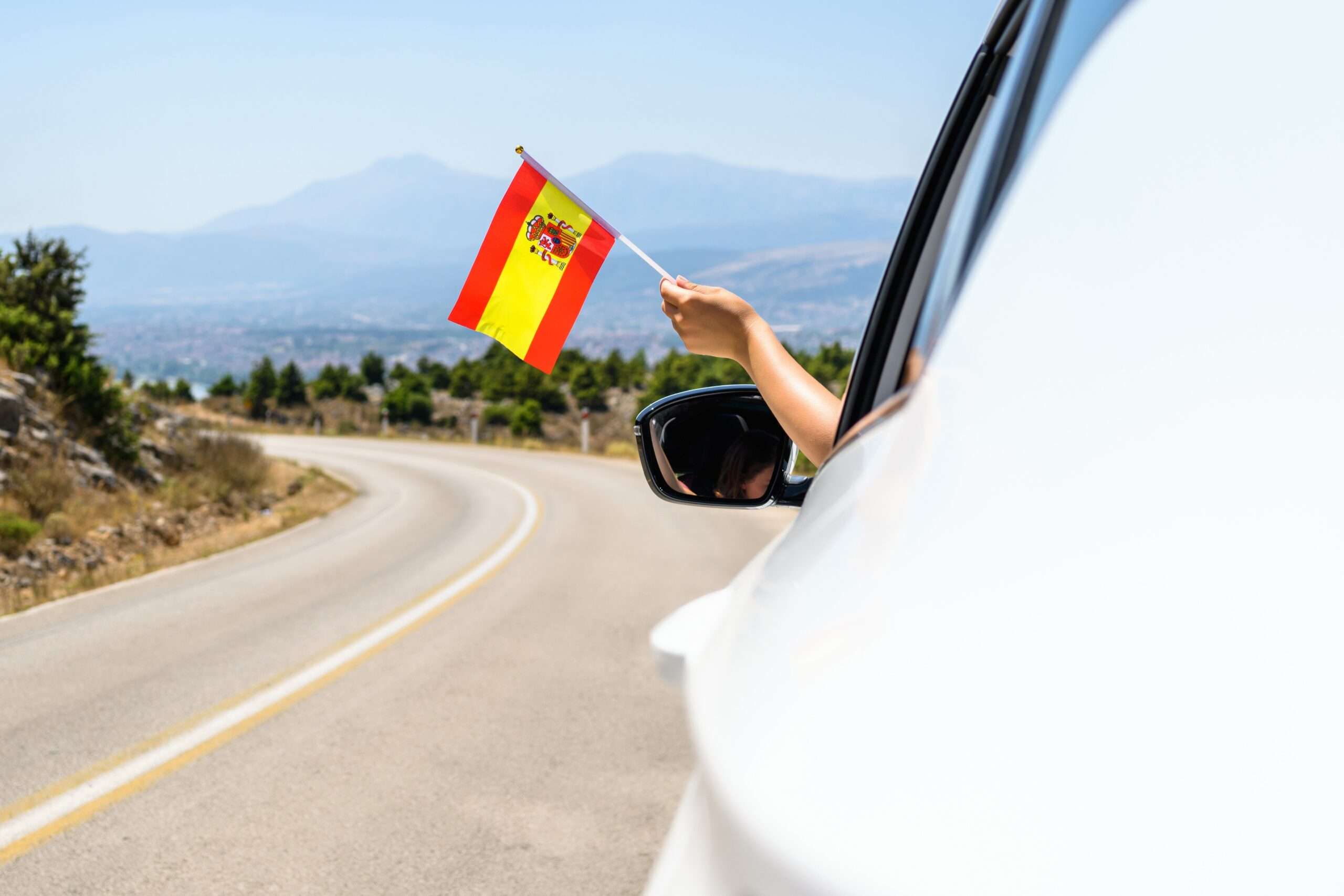 車の窓からスペイン国旗を振る人。