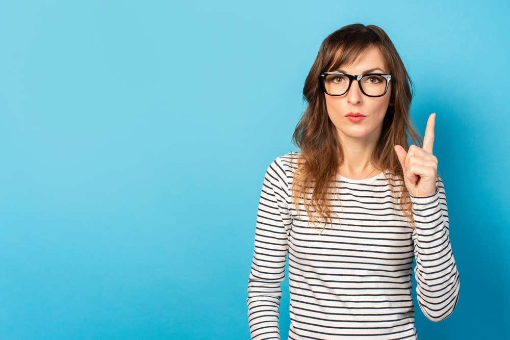 スペインで眼鏡をかけ、縞模様の T シャツを着て指を指す女性。