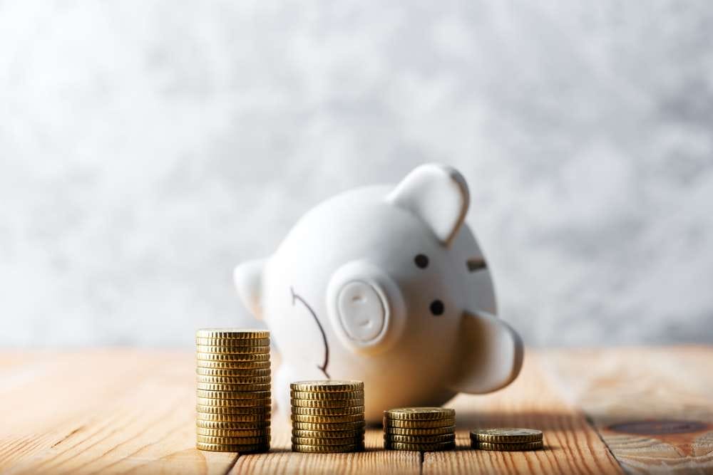 白い貯金箱が 4 枚の金貨の山の後ろに横たわっており、古典的なスペインの富を彷彿とさせる繁栄感を呼び起こします。