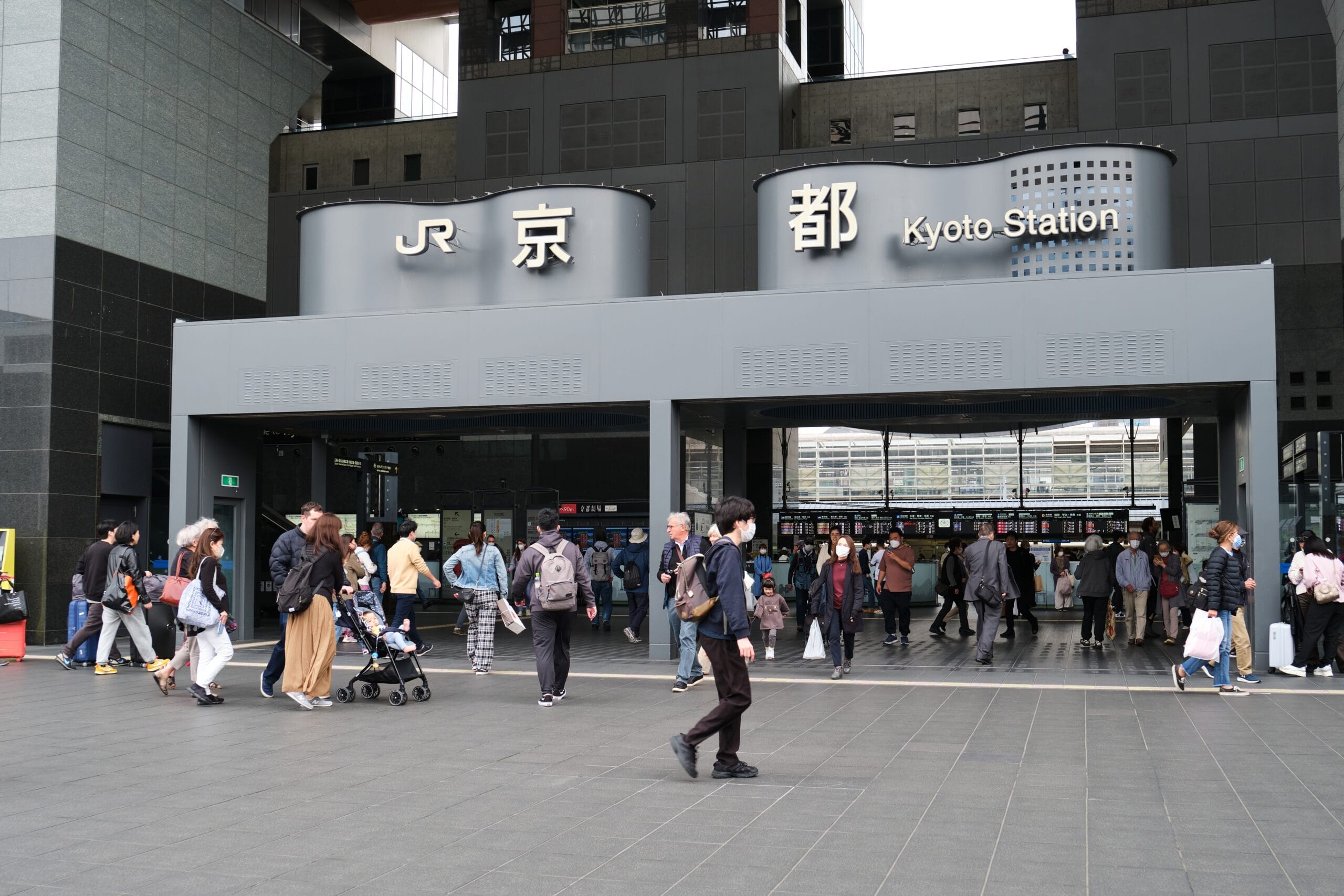 京都駅には人々が出入りしており、入口の上には「JR」と「京都駅」と書かれた看板が掲げられています。近くの居心地の良いカフェでは、京都の活気に満ちた雰囲気を楽しみながら学びたい人向けにマンツーマンスペイン語教室を開催しています。.