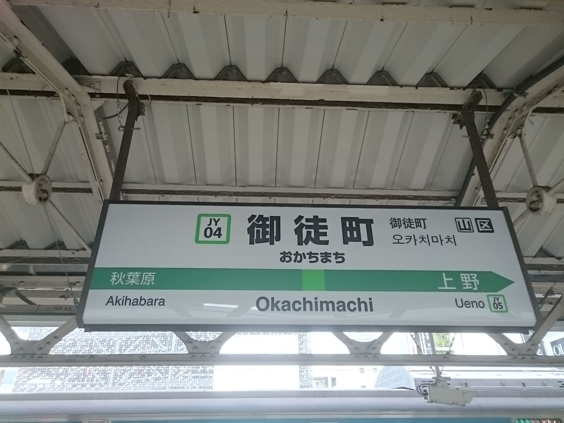 御徒町の駅標識は、秋葉原と上野への通勤者を案内しており、近くにはスペイン語教室マンツーマンがあり、個別の言語レッスンを提供しています。.